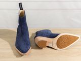 a close up of a pair of blue sued shoes on a wooden table