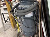 un dépoussiéreur posé à côté d'un tas de vieilleries dans un garage