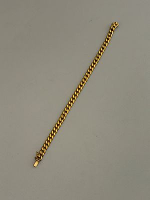 un bracelet en or sur une surface blanche