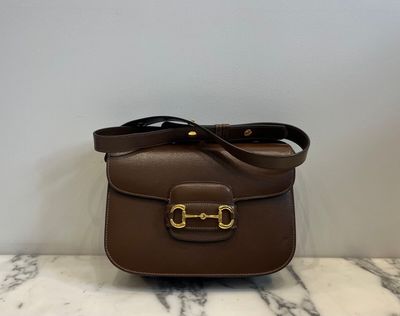 a brown leather bag with a gold buckle on the front