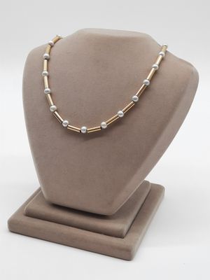 un collier en or et en argent orné de perles, porté par un mannequin