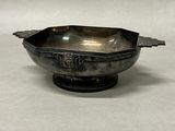 a silver bowl with a handle on a white surface