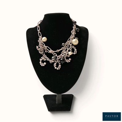 une chaîne en argent et un collier de perles présentés sur un mannequin