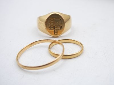 two gold rings and a gold signet on a white surface