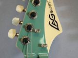 a close up of a green electric guitar with a wooden neck