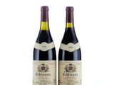 two bottles of red wine sitting next to each other on a white surface