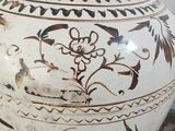 a white vase with black and brown designs on it