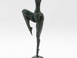 a bronze statue of a woman standing on one leg with her arms outstretched