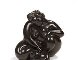 sculpture of a woman sitting on her knees on a white surface