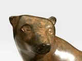 a bronze statue of a bear sitting on a white surface