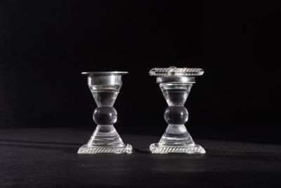 pair of clear glass candlesticks on a black background