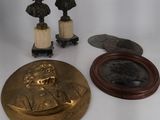 three bronze busturines and a mirror on a white surface