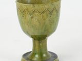 a green cup that is sitting on a stand