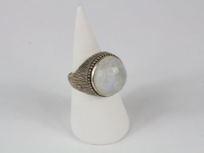 un gros plan d'une bague ornée d'une pierre blanche posée au sommet d'un cône blanc