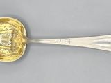 une cuillère ancienne en argent avec un manche en or sur un fond gris
