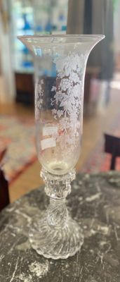 un vase en verre posé sur une table, à côté d'une horloge