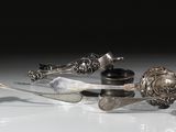 Plusieurs objets en argent sont posés sur une surface blanche
