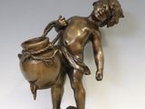 statue en bronze représentant un garçon portant un pot sur un rocher