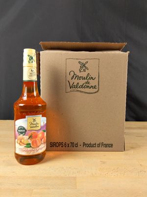 une bouteille de jus d'orange posée à côté d'un carton sur une table en bois
