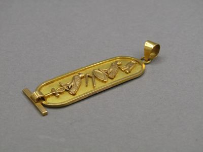 un gros plan sur un pendentif plaqué or orné d'un motif égyptien