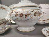 a white and gold teapot and saucer set on a table