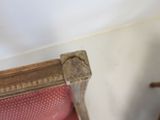 a wooden chair with a red upholstered seat next to a white wall