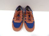 pair of blue and brown sneakers with orange laces sitting on a white surface