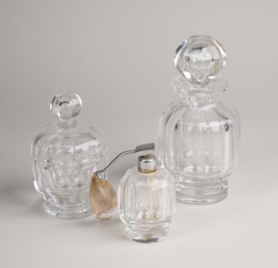 trois flacons de parfum en verre transparent ornés de coquillages, posés sur un fond blanc