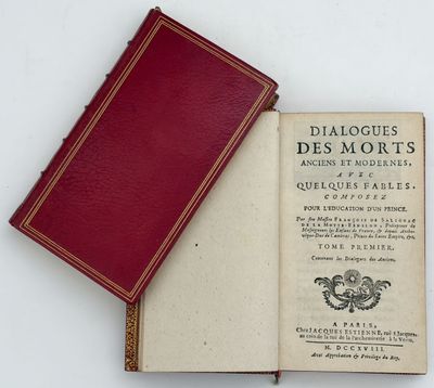an old book sitting on top of a white table next to a red book