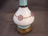 a white vase with a pink flower on it on a table