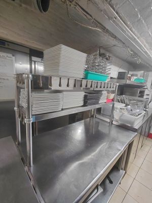 des plans de travail en acier inoxydable dans une cuisine professionnelle, sur lesquels sont posés de nombreux plats