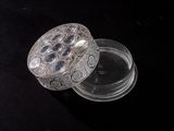 a glass box with a silver lid on a black surface