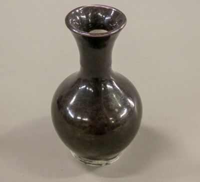 a small black vase sitting on a white table