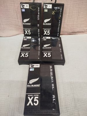 six boxed boxes of all blacks cigarettes sitting on a bed