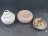 un vase blanc, un bol et une assiette posés sur une table