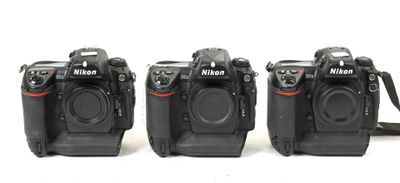 three cameras sitting side by side on a white surface