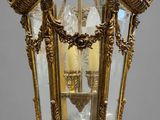 an antique brass hanging light fixture with clear glass panels and ornate carvings