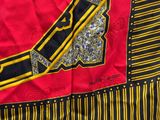 a close up of a red and black scarf with a knife on it