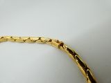 a close up of a gold bracelet on a white surface