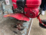 a man standing next to a red lawn mower on the sidewalk