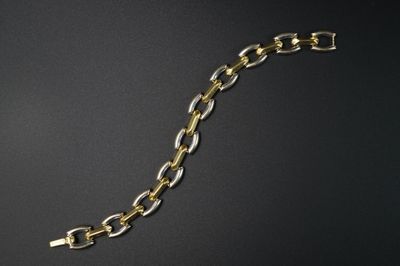 gros plan d'un bracelet en chaîne en or sur une surface noire