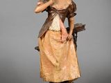 figurine représentant une femme en robe et chapeau tenant un oiseau