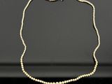un collier de perles blanches muni d'un fermoir en or sur un fond noir