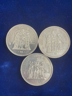 three british silver sovereigns on a blue velvet surface
