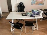 une table blanche avec deux chaises et un ordinateur portable posé dessus