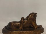bronze statue of a horse laying on its back on a marble base