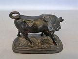 bronze statue of a bull on a base on a white surface