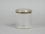 a small glass jar with a silver lid on a white surface
