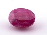 a pink ruby stone on a white surface
