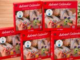 quatre calendriers de l'Avent pour enfants, dans des boîtes rouges, posés sur une table en bois